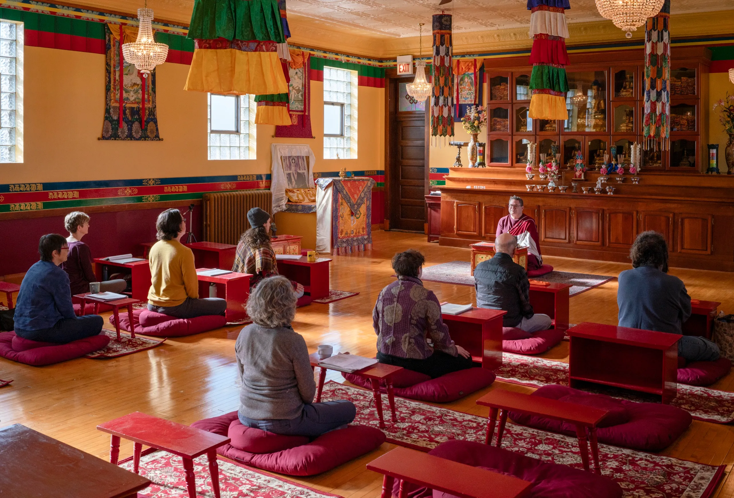 A Sunday practice session in the shrine room, practitioners seated at low red tables