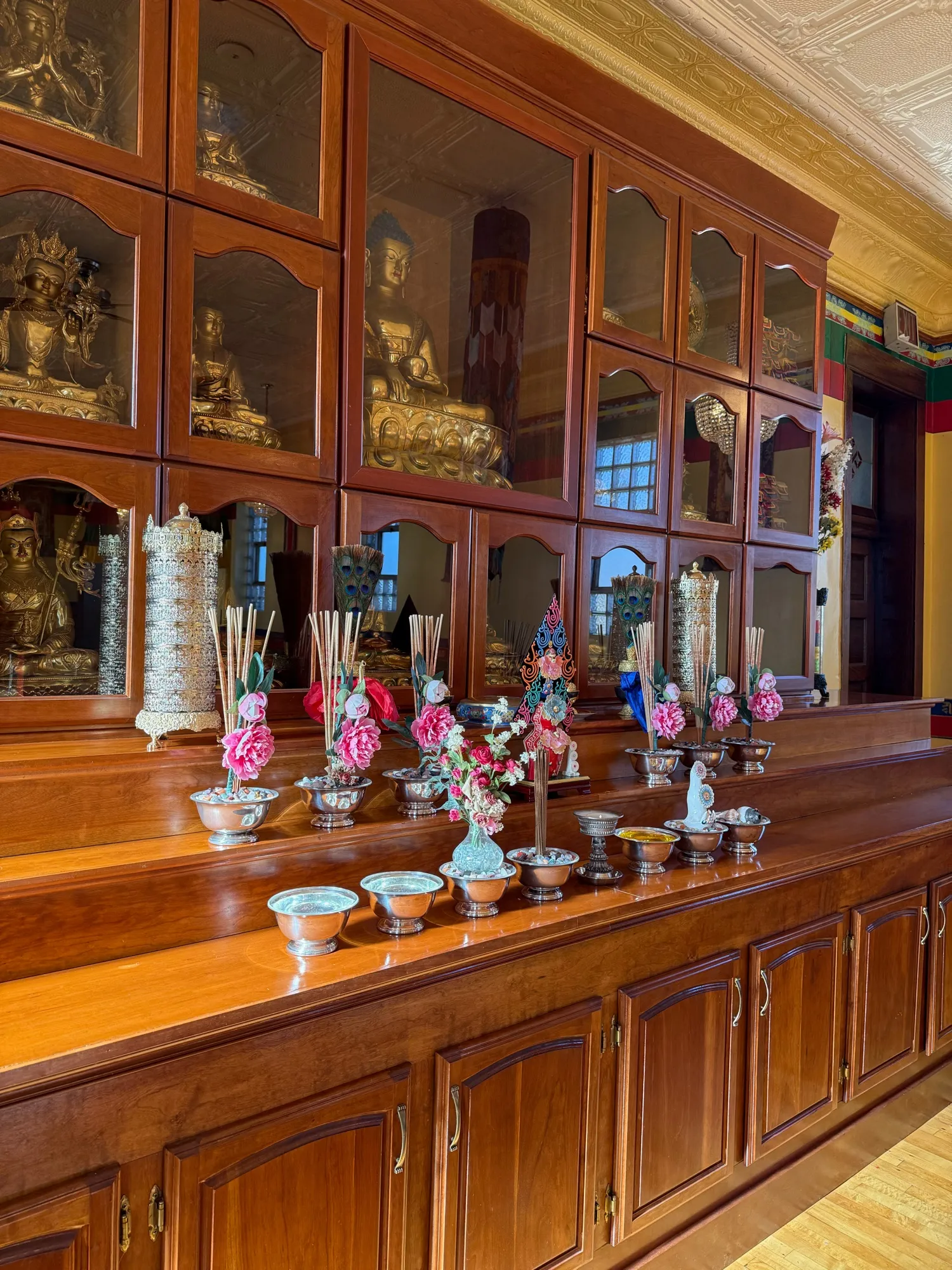 Offering bowls, flowers, and incense arranged on the polished wooden shrine at Chicago KTC