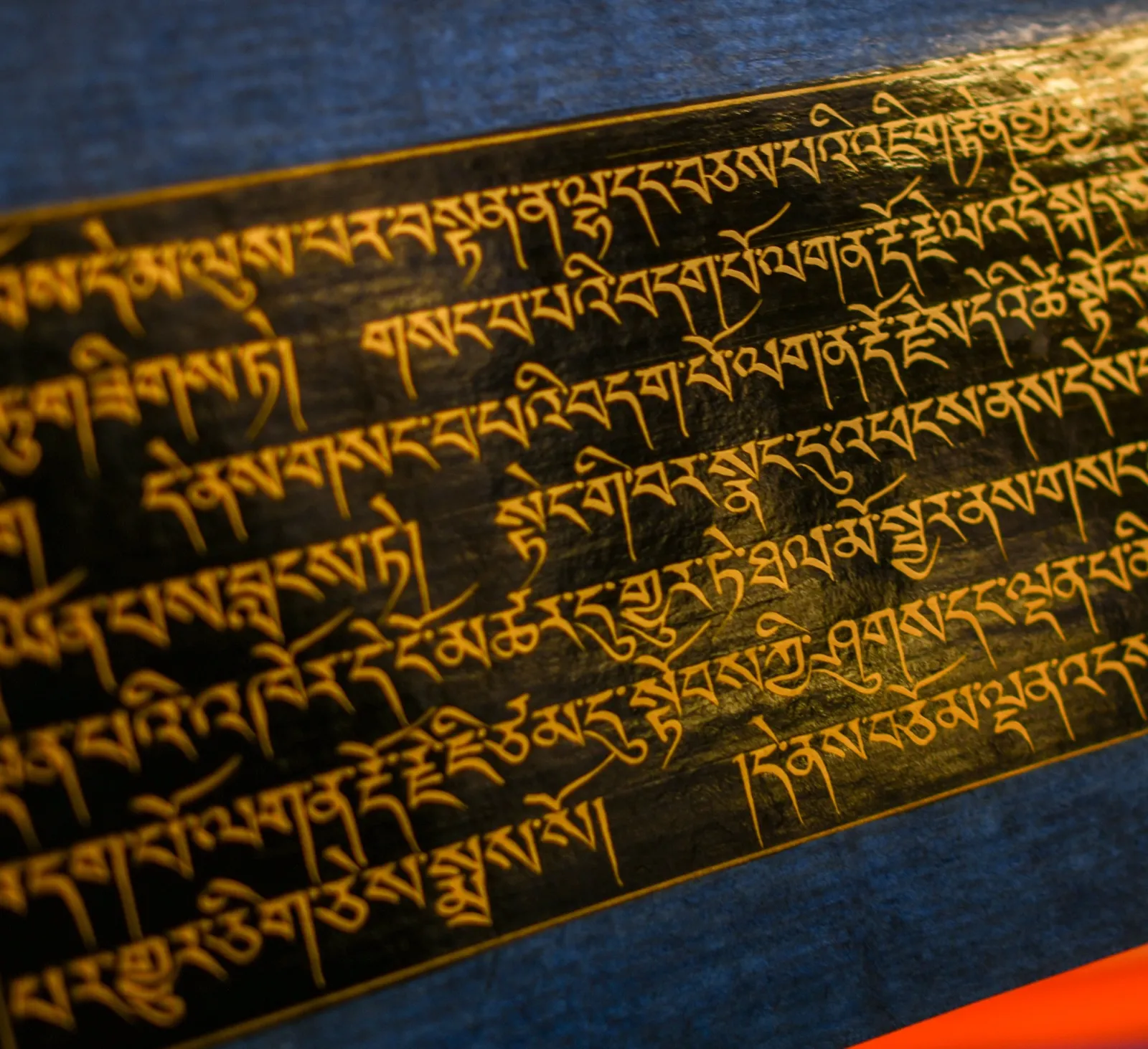 Gold Tibetan calligraphy on the dark pages of a Kangyur volume