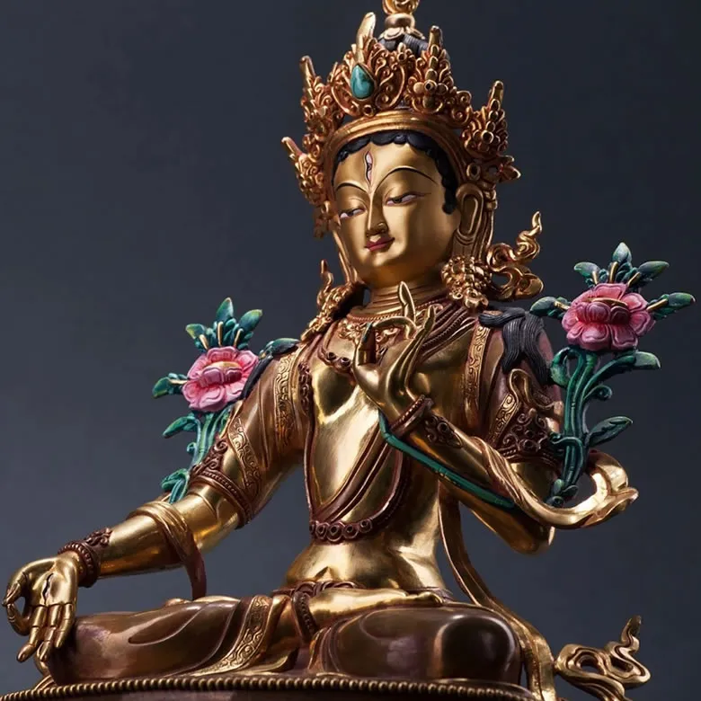 Gilt bronze Tara statue adorned with pink lotus flowers, seated in the posture of active compassion