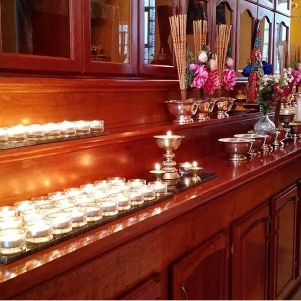 Rows of butter-lamp offerings glowing on the wooden shrine
